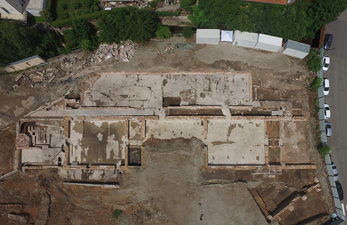 Vue aérienne de la caserne convertie en filature. A gauche, le local de la salle des machines avec la base octogonale de la cheminée. Au-dessus, des bâtiments annexes édifiés sur le canal dit des moulins.  J. Plumereau © Archéologie Alsace